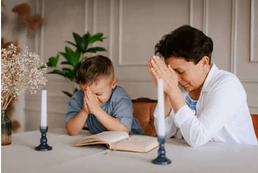 Mother and her child close their hands and pray for the family