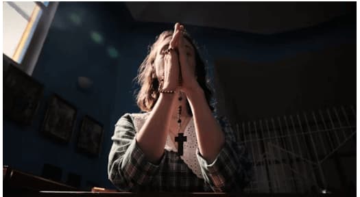 A woman praying, folding her hands